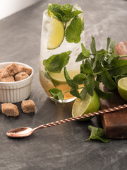 Refreshing mint cocktail mojito with rum and lime, cold drink or beverage with ice on black background