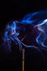Um incenso queimando e emitindo fumaça com um fundo preto.