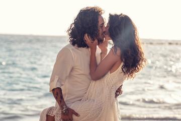 Happy cheerful couple kissing and hugging on the beach, spending time together.
