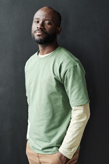 Portrait of African young handsome man in casual clothing looking at camera while standing against the black background