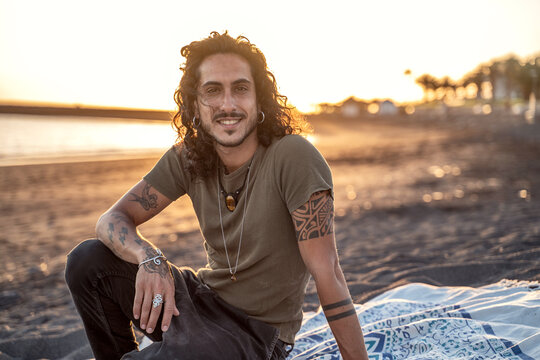 Happy relaxed handsome man sitting on the beach.