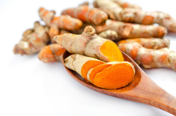 Closed up fresh organic sliced turmeric root in wooden spoon on white background