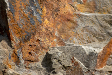 Raw rock in orange with minerals and metals as natural stones background with crushed and rough material at a rough coast or rocky beach show stone quarry and sandstones in broken surface granite form