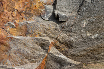 Raw rock in orange with minerals and metals as natural stones background with crushed and rough material at a rough coast or rocky beach show stone quarry and sandstones in broken surface granite form