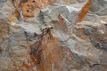 Raw rock in orange with minerals and metals as natural stones background with crushed and rough material at a rough coast or rocky beach show stone quarry and sandstones in broken surface granite form