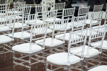 Glass chairs stand in a row in a beautiful wedding outing ceremony