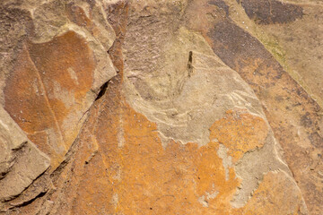Raw rock in orange with minerals and metals as natural stones background with crushed and rough material at a rough coast or rocky beach show stone quarry and sandstones in broken surface granite form