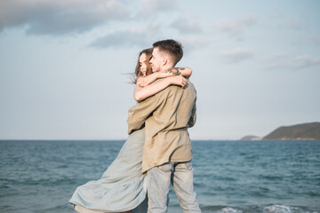 Couple in love standing on the beach and cuddling. Wearing sunglasses and casual clothes. Seaview. High quality photo