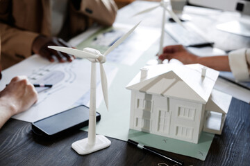 Close-up of model of new modern building on the table with architects working together at the table