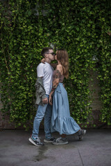 Fototapeta na wymiar Romantic Couple kissing in the park. Wearing sunglasses and casual clothes. green background. Millennials. High quality photo 