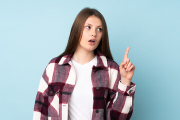 Teenager caucasian girl isolated on blue background thinking an idea pointing the finger up