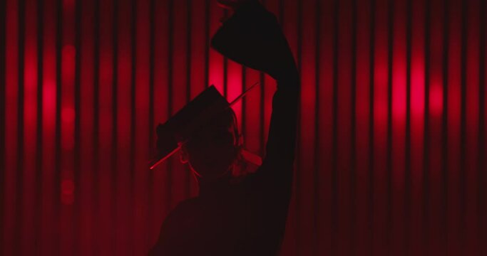 Beautiful hat dressed girl dancing latin dance . Professional female dancer dancing flamenco , rumba or salsa on red background with lines . Spanish dance movements . Shot ARRI ALEXA Cinema Camera .
