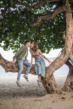 Lovely Couple sitting on the tree and kissing. Millennials. Romantic picture. High quality photo 