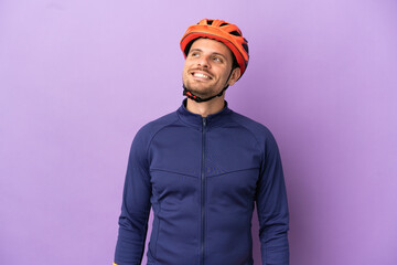 Young Brazilian cyclist man isolated on purple background thinking an idea while looking up