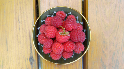 Red raspberries on a beautiful plate. A beautiful, juicy, environmentally friendly food product.