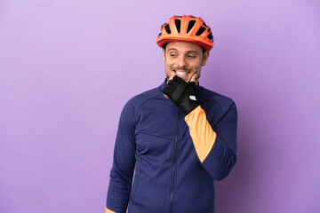 Young Brazilian cyclist man isolated on purple background looking to the side and smiling