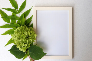 Photo frame with green leaves on white background with shadows. Mockup invitation. Top view, copy space