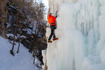 Man climbing on a frozen steep slope, passing between large bumps, ridges, and icicles