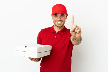 pizza delivery man with work uniform picking up pizza boxes over isolated  white wall showing and lifting a finger
