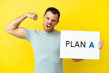 Brazilian man over isolated purple background holding a placard with the message PLAN A doing strong gesture