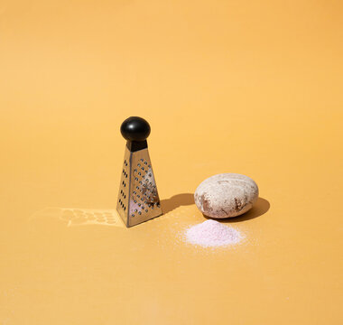 Sea stone turned to sand by a grater on yellow background. Minimal concept.