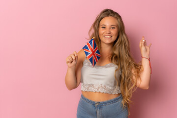 Young woman holding united kingdom flag looking positive and happy standing and smiling with a confident smile showing teeth
