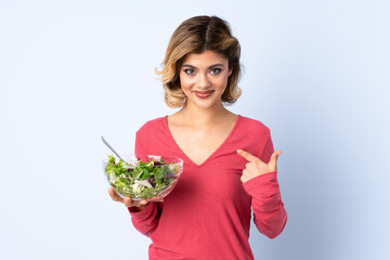 Teenager woman with salad isolated on blue background with surprise facial expression