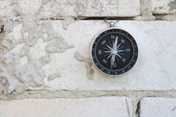 Classic navigation compass on brick wall background as symbol of tourism with compass, travel with compass and outdoor activities with compass