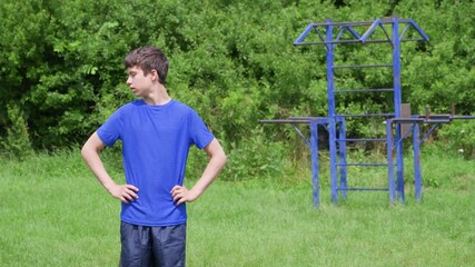 teenage boy exercising outdoors, sports ground in the yard, he does a warm-up, healthy lifestyle - Powered by Adobe
