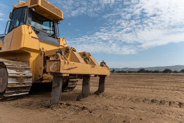 Heavy grading equipment vehicles resting its claws on the hard packed dirt that has been graded downn to proper elevation.