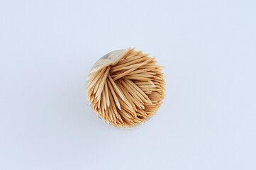 Wooden toothpicks in round package on white background close-up.