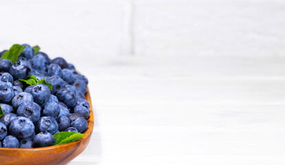 Blueberries With a Green Mint leaf in a Wooden Bowl on a white top view, Summer Freshly Berry, Copyspace