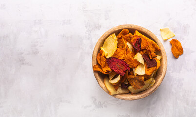Vegetable chips in bowl top view on concrete background