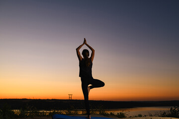 Fototapeta na wymiar Female silhouette stand in tree yoga positon at sunrise horizon, find balance in healthy life