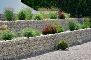 Geneigtes Wohngrundstück, neu terrassiert mit Stahlgitter-Gabionen mit Natursteinfüllung und initiale Hinterpflanzung mit Gartenpflanzen © Hermann