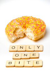 An Iced Ring Donut On A White Background With A Bite Taken Out and A Sign Reading Only One Bite