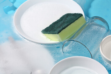 Dishware and sponge in water . Wash utensil after used.
