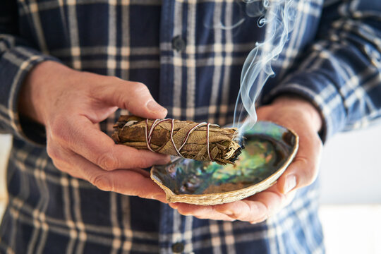 Mann r&auml;uchert mit einem Smudge Stick Kr&auml;uterb&uuml;ndel Wei&szlig;er Salbei, Yerba Santa  das Haus - atmosph&auml;rische Reinigung