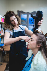 Side view of a woman customer getting a new hairstyle by female hairdresser.