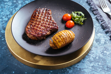 steak with potatoes and cherry tomatoes on a blue background