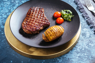 steak with potatoes and cherry tomatoes on a blue background