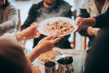 Friends at the table during a lunch. The boys pass each other a plate of homemade Italian pasta