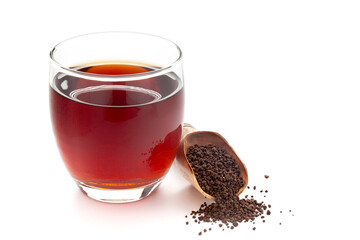 Close-Up of original  organic boiled water (Tea or kada ) with dry cut leaves of tea (Camellia sinensis) in a transparent glass cup over white background. Original residue in bottom of tea cup