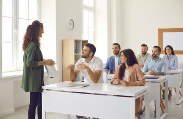 College teacher having class with group of interested adult male and female business course...