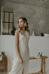 Pretty young curly woman in linen dress looks away. Portrait of blonde elegant lady with big white...