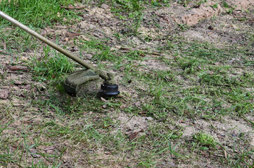 Trimmer mows the lawn. Concept of garden work. Lawn care with lawn mower, brush mower or an electric lawn mowing tool.