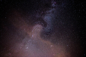 Fotografia nocnego nieba, ilustrująca obecność i działanie czarnej dziury na pobliską galaktykę.