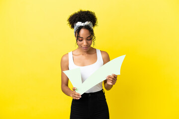 Young african american woman isolated on yellow background holding a check icon and looking it