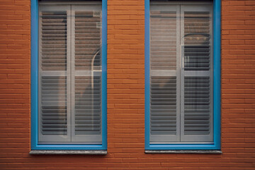 blue framed window with blinds in red brick wall