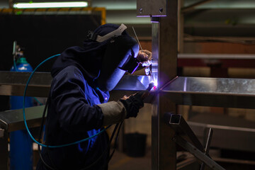 builder wear fireproof gloves for safety at work. Workers wearing industrial uniforms and welding...